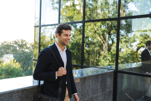 Confident young businessman carrying bag, standing outdoors