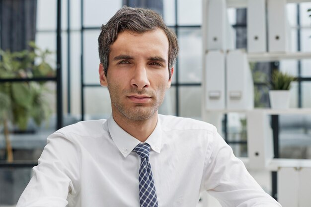 Confident young businessman posing in the office with his hands together