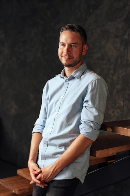 Confident young businessman standing near wooden ladder portrait