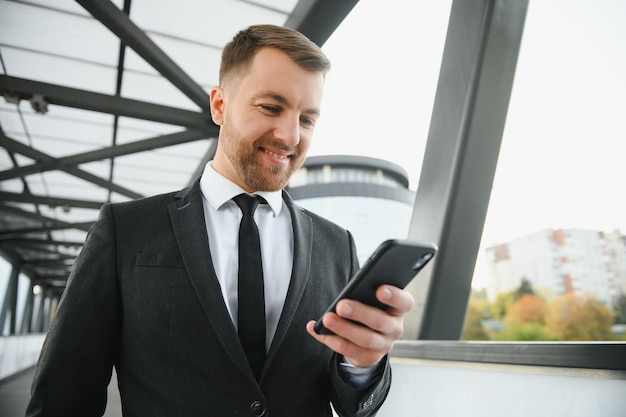 Confident young businessman using cell phone in the city