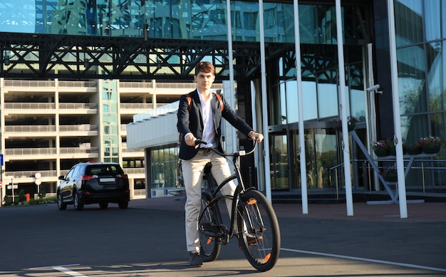 Confident young businessman walking with bicycle on the street in town.