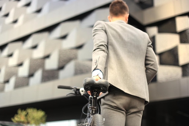 Confident young businessman walking with bicycle on the street in town