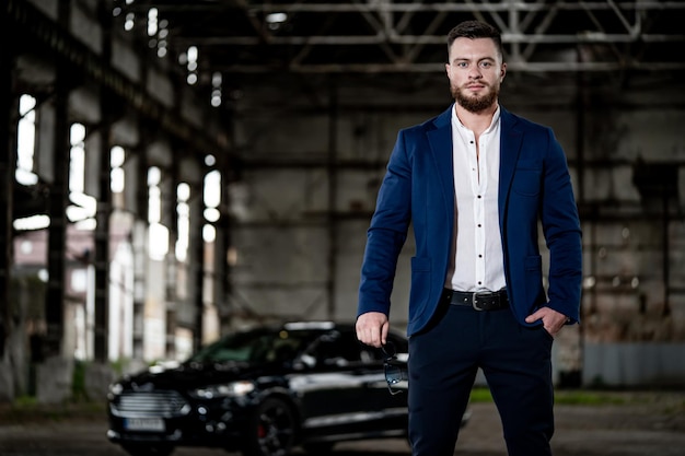 Confident young businessman with car standing outdoor Successful luxury person