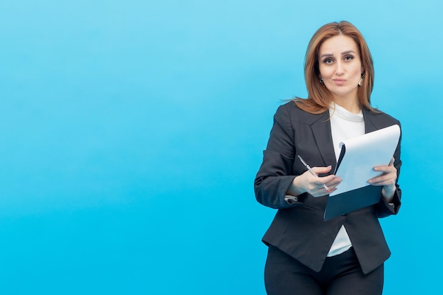 Confident young businesswoman holding notebook and looking at the camera