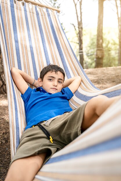 Confident young caucasian boy sitting in hammock on vacation