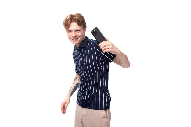 Confident young european blond guy in a striped polo shirt with a tattoo on a white background