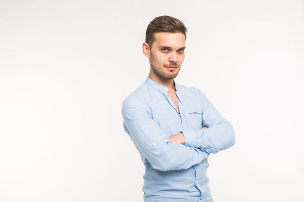 Confident young handsome man keeping arms crossed and smiling on white background with copy space