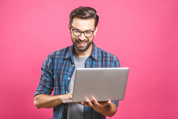 Confident young handsome man in shirt holding laptop and smiling 