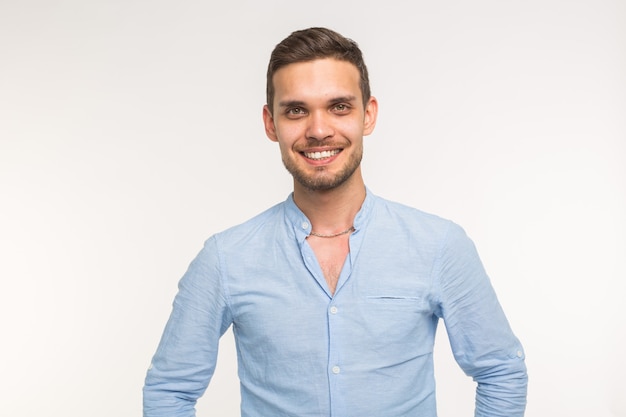 Confident young handsome man smiling on white wall.