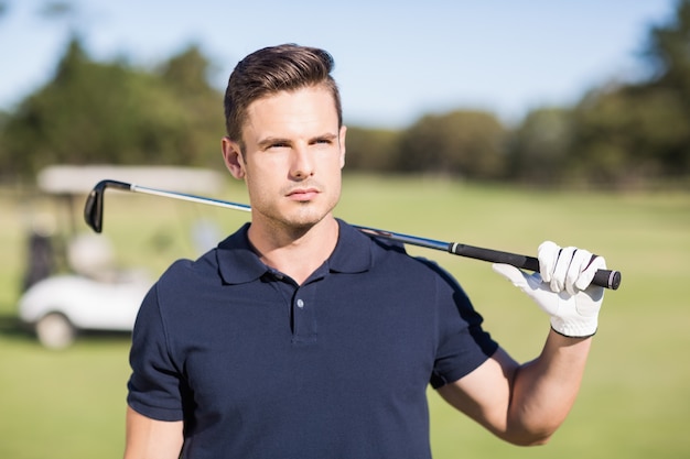 Confident young man carrying golf club