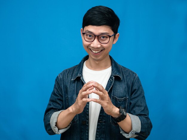 Confident young man jeans shirt smile looking at camera blue background