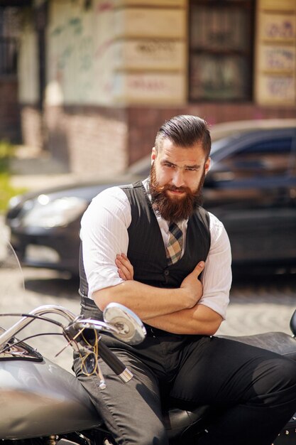 Confident young man  sitting on a motorbike with his arms crossed