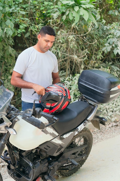 Confident young man in white T-shirt and jeans on a motorcycle in open air