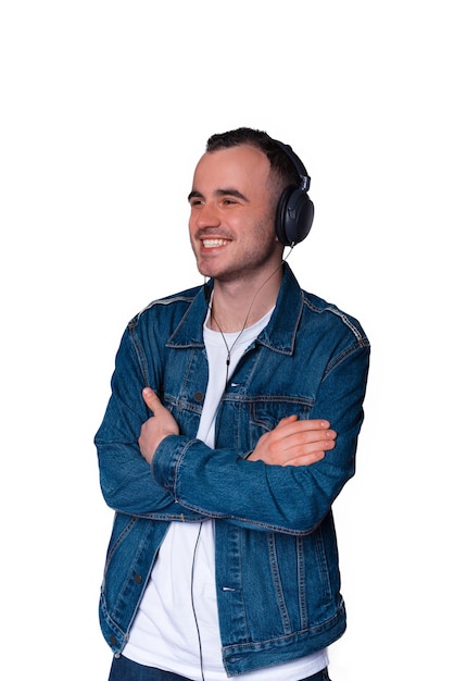 Confident young man with arms crossed is listening to the music or audio book in earphones.