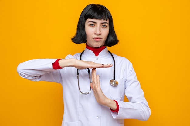 Confident young pretty caucasian woman in doctor uniform with stethoscope gesturing time out sign 