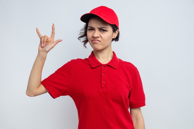 Confident young pretty delivery woman gesturing horns sign