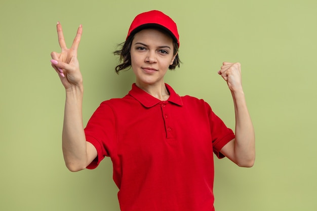 Foto fiduciosa giovane bella donna delle consegne che tiene il pugno e gesticola il segno della vittoria