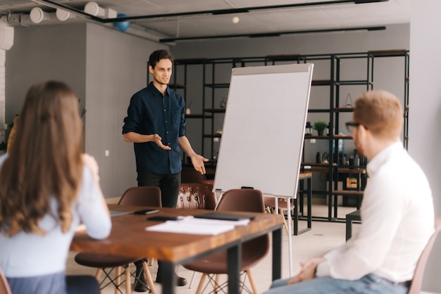 Confident young speaker coach gives corporate presentation on whiteboard