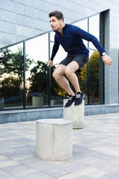 Confident young sportsman doing stretching exercises outdoors