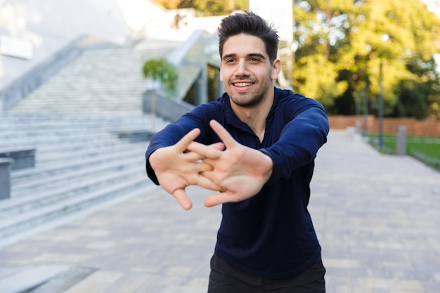 Foto fiducioso giovane sportivo facendo esercizi di stretching all'aperto