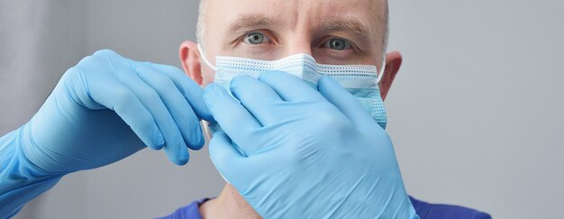 Confident young surgeon doctor in latex protective gloves wearing medical mask on face. Man professional medic.