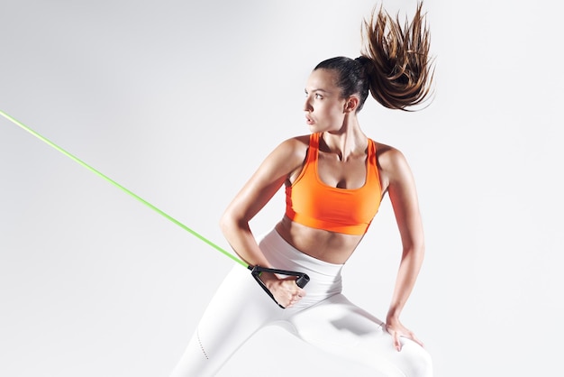 Photo confident young woman exercising with resistance band against white background