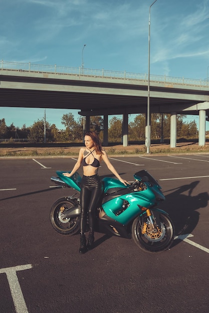 Confident young woman sitting on motorbike on parking area