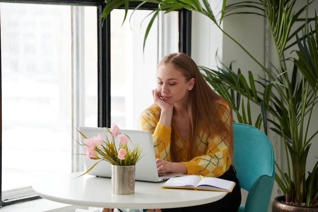 Confident young woman in smart casual wear working on laptop