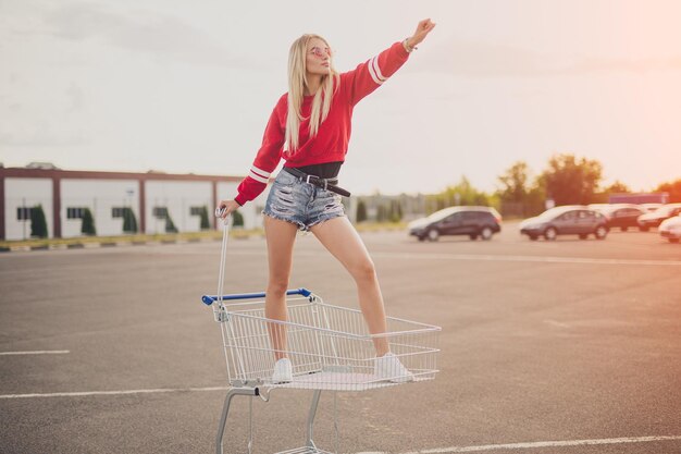 Photo confident young woman standing in shopping trolley