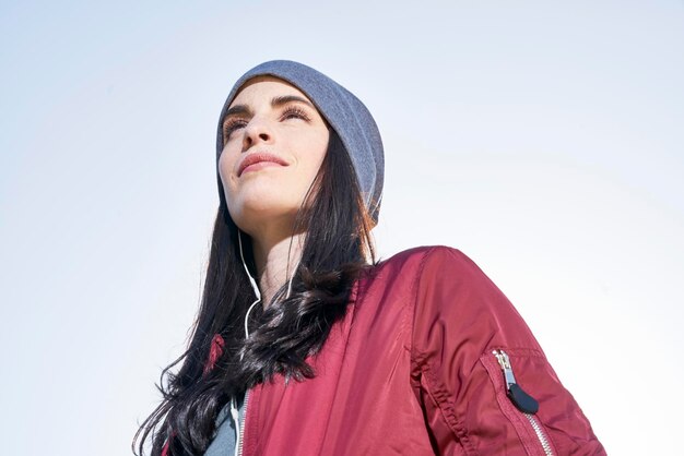 Confident young woman with earbuds outdoors