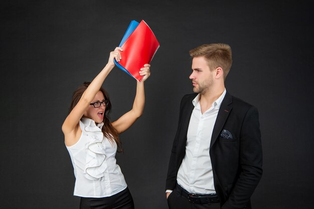 Conflicten op de professionele werkplek. Agressieve vrouw huurmoordenaar met boeken. Conflicthantering. Collega's vechten. Werkplek gevecht.