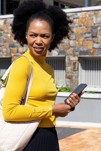 Confused african american businesswoman walking with tablet and handbag. Global business, finances, on the go and office concept.