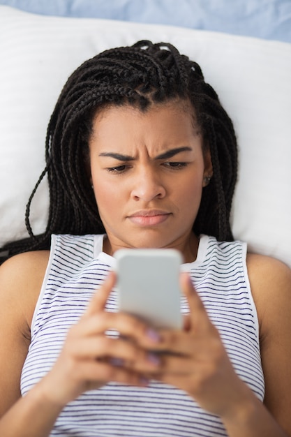 Confused African girl using smartphone