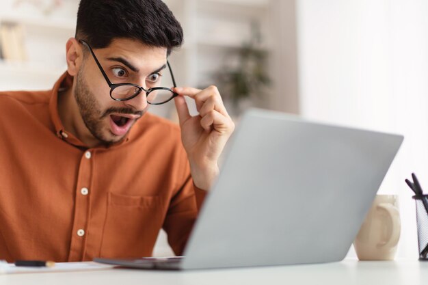 Confused arab guy using laptop looking at screen