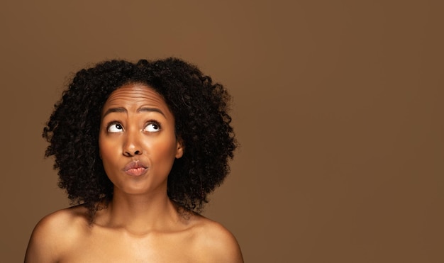 Confused beautiful halfnaked millennial black woman looking at copy space