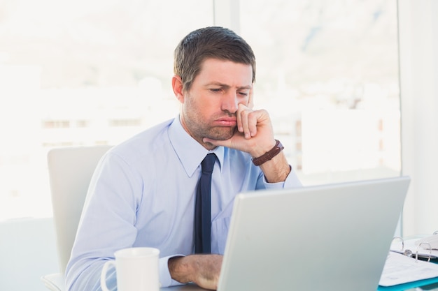 Confused businessman looking at his laptop