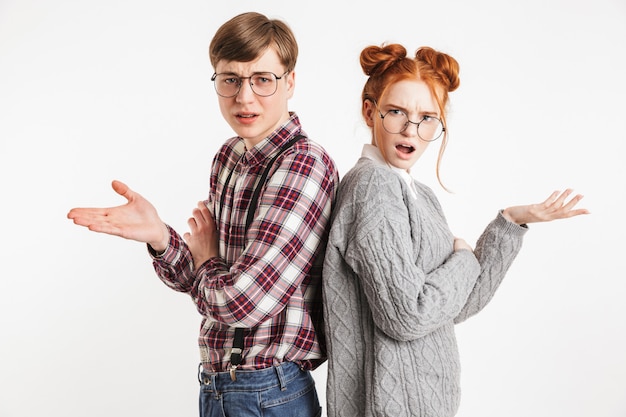 Confused couple of school nerds standing back to back