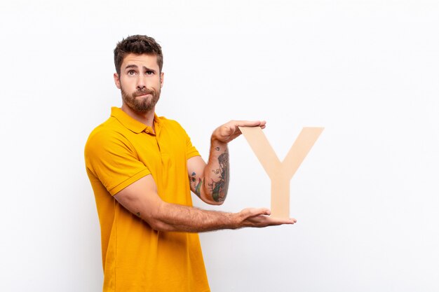 confused, doubtful, thinking, holding the letter Y of the alphabet to form a word or a sentence.