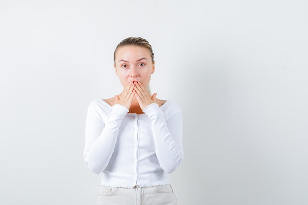 Confused girl is closing her mouth on white background