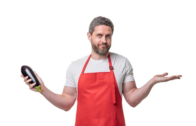 Confused man in apron with eggplant vegetable isolated on white