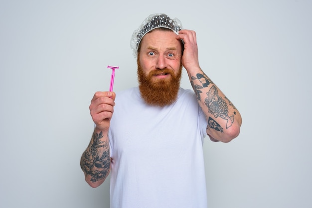 Photo confused man wants to adjust the beard with a razor blade