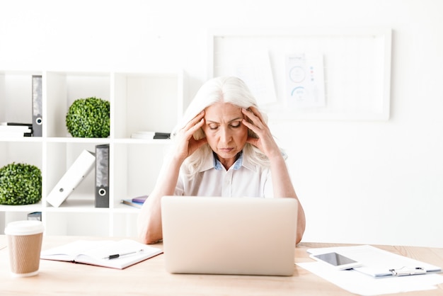 Confused mature woman using laptop computer.