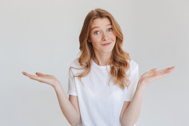 Confused redhead woman isolated on white wall.