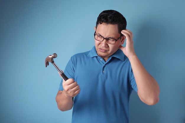 混乱した無能な男がハンマーを見ている