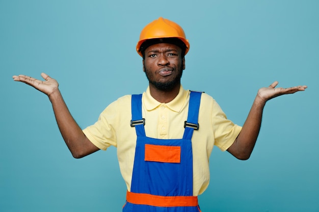 confused spreading hands young african american builder in uniform isolated on blue background 6