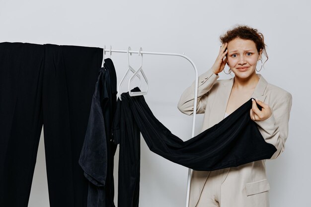 Confused teenager girl holding garment against wall