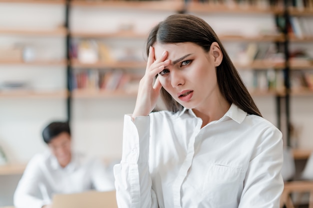 Confused and tired woman in white shirt working in the office