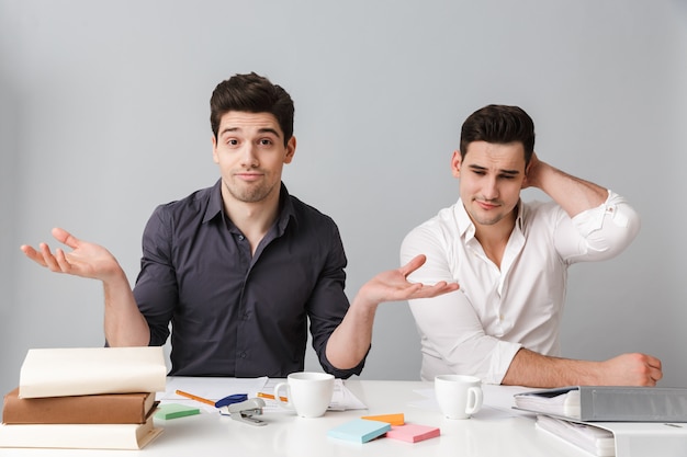 Confused two young business men coworking.