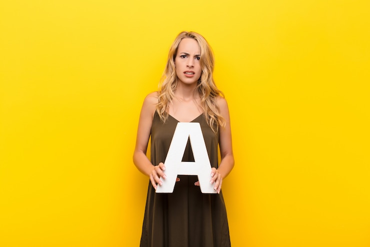 फोटो confused woman holding the letter a of the alphabet to form a word
