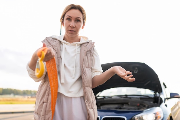 Confused woman with wires for charging the battery confused\
looking at the camera of a stationary